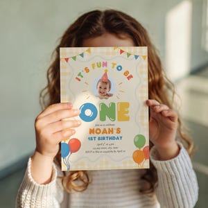 May include: A birthday invitation with the text "It's fun to be ONE" and a photo of a baby wearing a party hat. The invitation has a yellow gingham background and colorful balloons. The invitation is for Noah's 1st birthday.