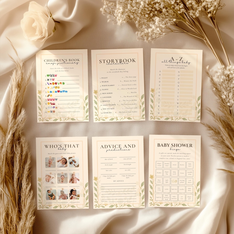 Puede incluir: Un conjunto de tarjetas de juegos para baby shower con bordes florales y de hojas. Los juegos incluyen "Children's Book Emoji Pictionary", "Storybook Characters" y "Baby Shower Bingo". Las tarjetas son beige con detalles verdes y amarillos.