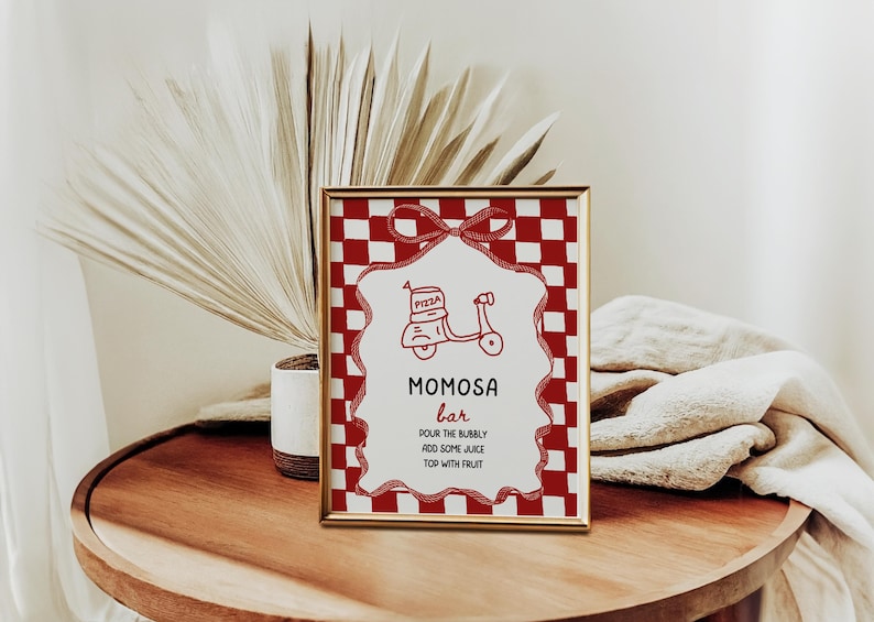 May include: A framed sign with a red and white checkered border and a gold frame. The sign reads "MOMOSA bar" with instructions below. A red scooter graphic is at the top. The sign is on a wooden table.