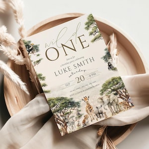 May include: A safari-themed birthday party invitation with the text "Wild One". The invitation features illustrations of animals and trees on a beige background. Details include the name "LUKE SMITH", date, and time.