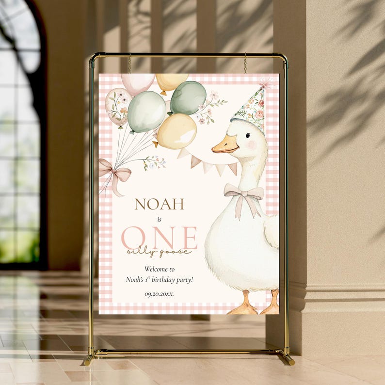 May include: A party sign featuring a cartoon goose wearing a floral party hat and bow tie, holding balloons. The sign reads "Noah is One silly goose" with a welcome message for Noah's first birthday party. The background has a pink gingham pattern.