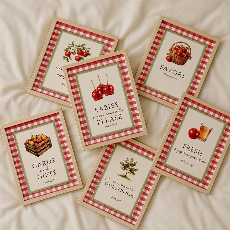 Op de afbeelding: Zes ingelijste borden met appelthema-illustraties en tekst. De borden hebben een rood-witte geruite rand en houten frames. Tekst omvat "Kaarten en cadeaus", "Baby's zijn lief, alsjeblieft", "Gunsten", "Vers appelsap" en "Gelieve het gastenboek te ondertekenen".