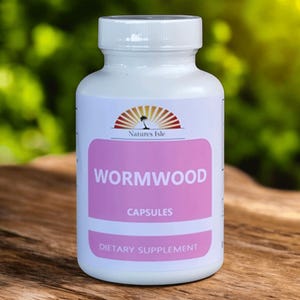 May include: A white bottle of "Wormwood Capsules" dietary supplement. The label features a pink rectangle with the product name in large white letters and the brand logo at the top. The bottle is on a wooden surface with a blurred green background.