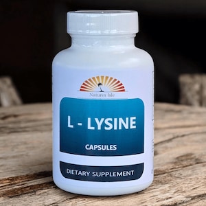 May include: A white plastic bottle of L-Lysine capsules. The label features the text "L-LYSINE CAPSULES" in white letters on a blue background, with "Natures Isle" logo above. The bottle is a dietary supplement.
