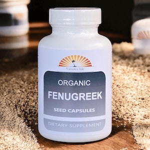 May include: A white bottle of "Natures Isle" organic fenugreek seed capsules. The label features a logo of a palm tree and sunburst. The text "Dietary Supplement" is at the bottom of the label. The bottle is on a wooden surface.