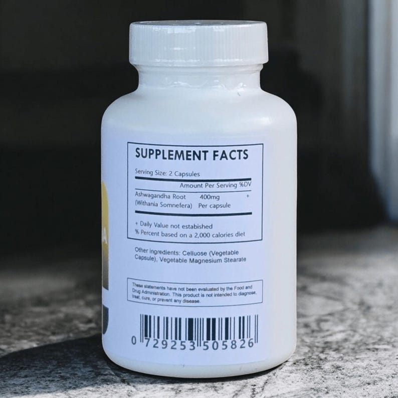 Op de afbeelding: Een witte supplementfles met een witte dop. Het etiket toont "SUPPLEMENT FACTS" en ingredi&euml;nteninformatie, waaronder "Ashwagandha Root" en "400mg". De fles bevat ook andere ingredi&euml;nten en een streepjescode.