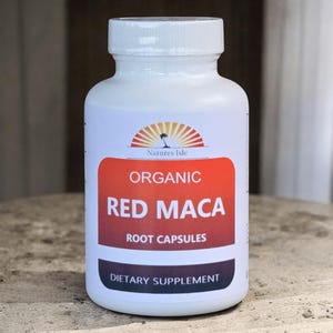 May include: A white bottle of "Organic Red Maca Root Capsules" dietary supplement. The label features a red and orange gradient with white text and a logo of a palm tree and sun. The bottle has a white cap.