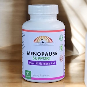 Puede incluir: Una botella blanca de suplemento dietético "Menopause Support" con una etiqueta morada y naranja. La etiqueta incluye la marca "Natures Isle" e indica "Mood & Hormone Aid". La botella contiene 90 cápsulas y está marcada como sin OGM y sin gluten.