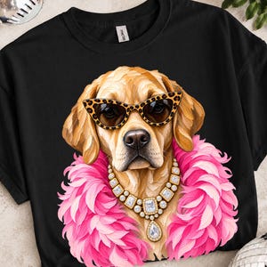 May include: A black t-shirt featuring a graphic of a golden retriever wearing leopard print cat-eye sunglasses, a pink feather boa, and a gold-toned statement necklace with clear rectangular crystals and a large teardrop-shaped pendant.