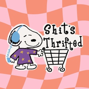 May include: A cartoon illustration of a white dog wearing blue headphones and a purple shirt with yellow stars, pushing a shopping cart. The text "Shit's Thrifted" is above the cart, set against a pink and orange checkered background.
