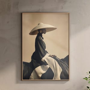 Op de afbeelding: Een ingelijste kunstdruk met een persoon die een grote, breedgerande strohoed en een lange zwart-witte jurk draagt. Het kunstwerk heeft een sepia-tint, wat een vintage esthetiek creëert. De persoon zit, in profiel, en draagt een gouden oorbel.
