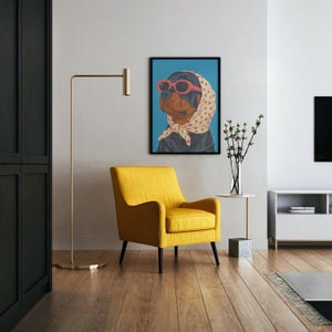 Puede incluir: Una impresi&oacute;n art&iacute;stica enmarcada con un Rottweiler con gafas de sol rojas y un pa&ntilde;uelo de lunares. La obra de arte cuelga sobre un sill&oacute;n amarillo con patas negras. Una l&aacute;mpara de pie dorada y una peque&ntilde;a mesa auxiliar completan la decoraci&oacute;n.
