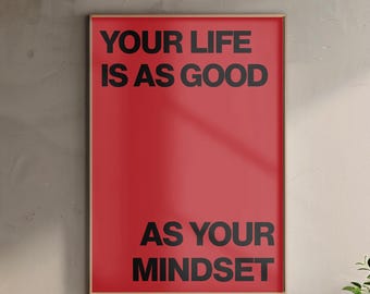Puede incluir: Un póster enmarcado con un fondo rojo y texto negro que dice "YOUR LIFE IS AS GOOD AS YOUR MINDSET". El póster tiene un marco delgado de color marrón claro y se muestra contra una pared de color neutro.