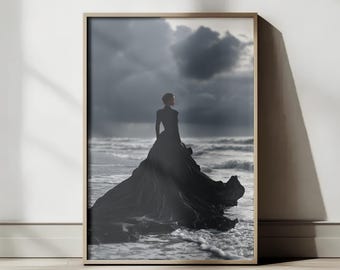 Può includere: Una stampa artistica incorniciata con una persona in un lungo abito nero in piedi nell'oceano. L'immagine è in scala di grigi, con un cielo drammatico e onde. La persona è vista da dietro.