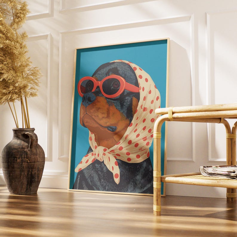 Puede incluir: Una impresi&oacute;n art&iacute;stica enmarcada que presenta un perro Rottweiler con gafas de sol rojas y un pa&ntilde;uelo de lunares. El retrato del perro est&aacute; sobre un fondo turquesa. La obra de arte se exhibe en una habitaci&oacute;n con un jarr&oacute;n y una mesa auxiliar de rat&aacute;n.