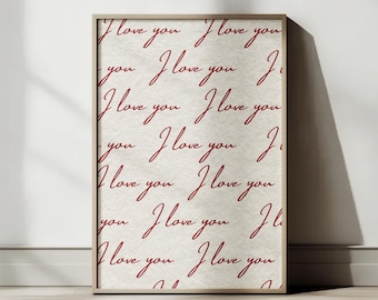 Può includere: Una stampa incorniciata con la frase "I love you" ripetuta in stile scritto a mano su uno sfondo color crema. Il testo è di colore rosso scuro e la cornice è marrone chiaro.