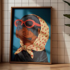 Puede incluir: Impresi&oacute;n art&iacute;stica enmarcada de un perro Rottweiler con gafas de sol rojas y un pa&ntilde;uelo amarillo con lunares. El perro tiene pelaje negro y marr&oacute;n, sobre un fondo azul. El marco es de color marr&oacute;n c&aacute;lido.