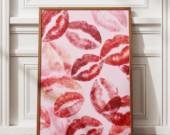 Può includere: Stampa incorniciata con un motivo di baci di rossetto rosso e rosa su sfondo rosa chiaro. La cornice in legno circonda l'opera d'arte, creando un elemento decorativo per pareti.