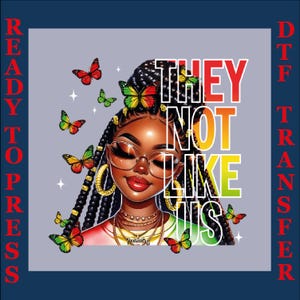 May include: A digital DTF transfer featuring a Black woman with glasses, gold jewelry, and butterflies. The text "THEY NOT LIKE US" is in a colorful font. The words "READY TO PRESS" and "DTF TRANSFER" are on the sides.