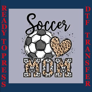 Peut inclure: Motif de transfert DTF Soccer Mom. Le motif présente un ballon de football, un cœur à imprimé léopard et le mot «MOM» dans un motif de ballon de football. Les mots «READY TO PRESS» et «DTF TRANSFER» sont sur les côtés.