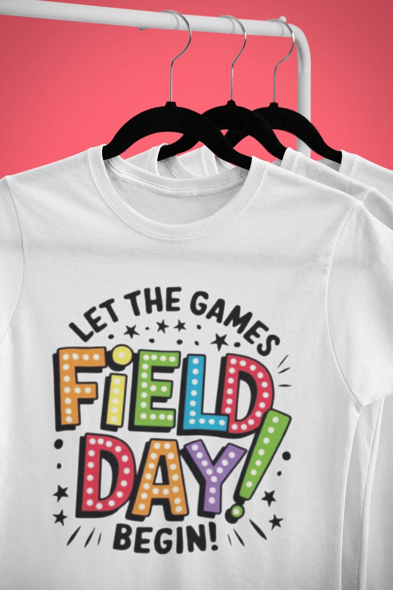 May include: White t-shirt with a colorful graphic that says "Let the games begin! Field Day!" The graphic is in a retro style with light bulbs around the letters.