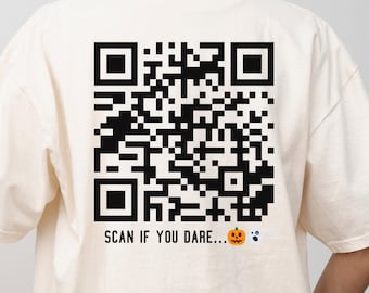 May include: Ivory-colored t-shirt with a large black QR code graphic on the back. The text "SCAN IF YOU DARE..." is printed below the code, along with a jack-o'-lantern and a ghost graphic.