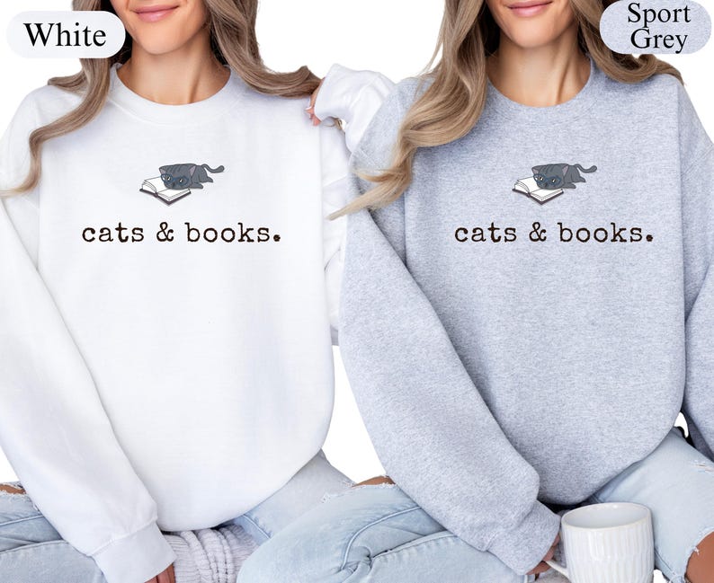 K&ouml;nnte beinhalten: Wei&szlig;e und graue Sweatshirts mit dem Text "cats & books". Jedes Sweatshirt hat eine kleine Grafik einer Katze auf einem Buch. Die Sweatshirts sind ein bequemer, l&auml;ssiger Stil.