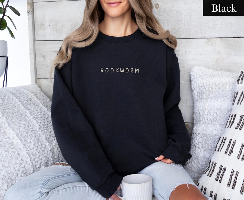 May include: Black crewneck sweatshirt with the word "BOOKWORM" embroidered in white. The sweatshirt is a solid black color and is made of a soft material. The sweatshirt is a casual style and is perfect for book lovers.