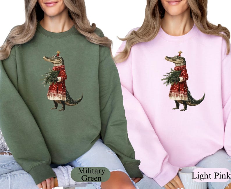 Pu&ograve; includere: Due felpe, una verde militare e una rosa chiaro, ciascuna con una stravagante illustrazione di un alligatore vestito con un abito rosso festivo, che tiene in mano un mazzo di verde. L'alligatore indossa una corona d'oro a forma di stella. Le felpe sono casual.