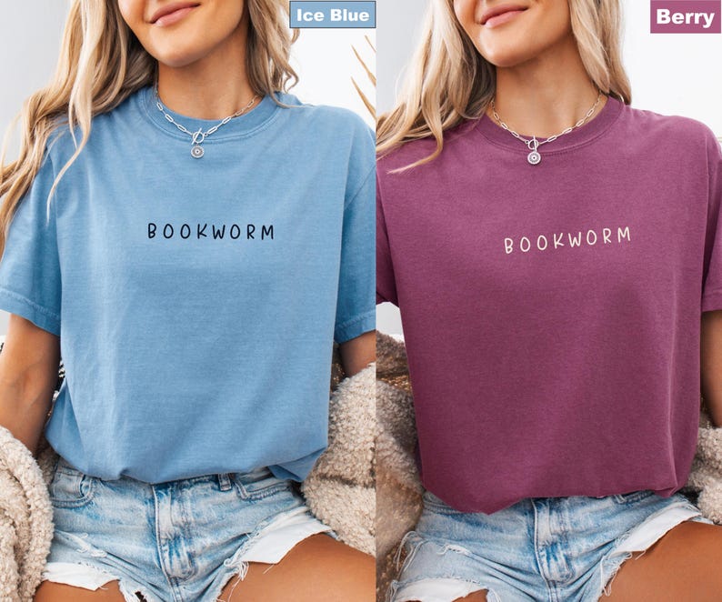 May include: Two short-sleeved t-shirts, one ice blue and one berry-colored. Each shirt has the word "BOOKWORM" printed in a contrasting color across the chest. The shirts are made of a soft material and are suitable for casual wear.