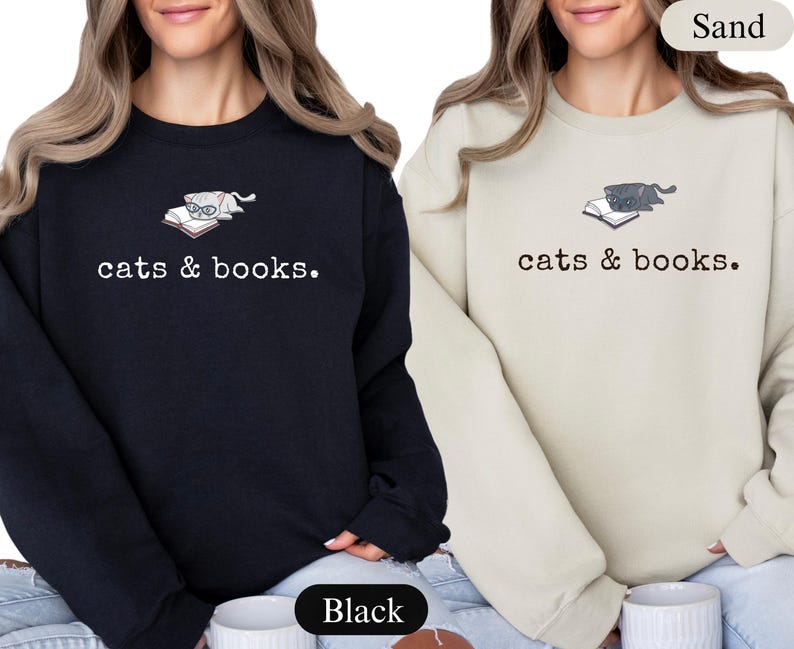 K&ouml;nnte beinhalten: Schwarze und sandfarbene Sweatshirts mit dem Text "cats & books". Jedes Sweatshirt zeigt eine Katzen-Grafik auf einem Buch. Das schwarze Sweatshirt hat eine Katze mit Brille, und das sandfarbene Sweatshirt hat eine graue Katze.