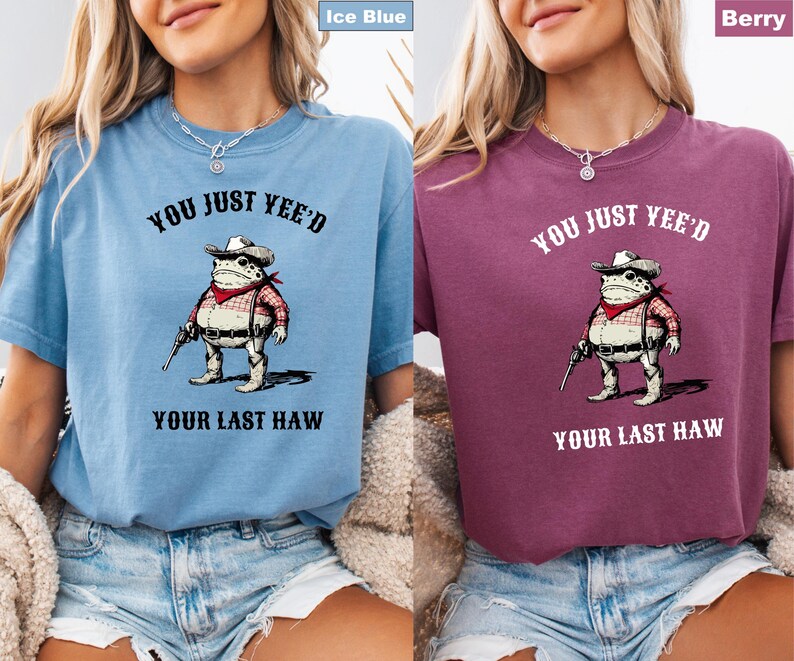 Puede incluir: Camisetas de color azul hielo y baya con el texto "YOU JUST YEE'D YOUR LAST HAW" encima y debajo de una rana de dibujos animados con sombrero de vaquero, pa&ntilde;uelo rojo y sosteniendo una pistola. Las camisetas son de manga corta.