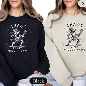 May include: Black and sand-colored sweatshirts with the text "CHAOS IS MY MIDDLE NAME". Each sweatshirt features a white illustration of a frog chef holding a whisk. The sweatshirts are a comfortable, casual style.