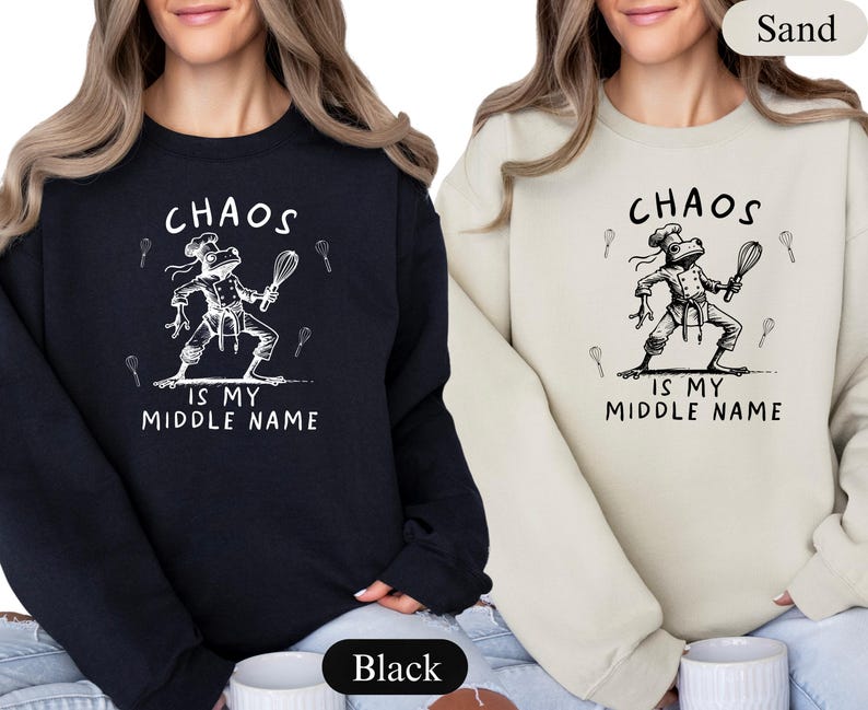 May include: Black and sand-colored sweatshirts with the text "CHAOS IS MY MIDDLE NAME". Each sweatshirt features a white illustration of a frog chef holding a whisk. The sweatshirts are a comfortable, casual style.