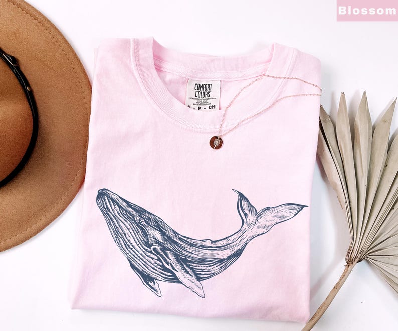 May include: A pink t-shirt with a black and white whale graphic. The shirt has the text "COMFORT COLORS" printed on the front.