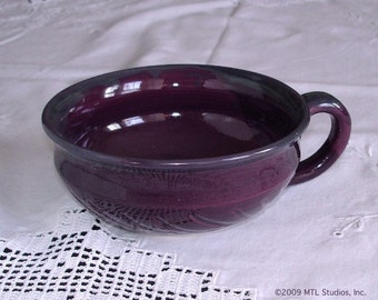 May include: A deep purple ceramic soup bowl with a rounded shape and a single handle. The bowl has a textured exterior and a smooth, glossy interior.