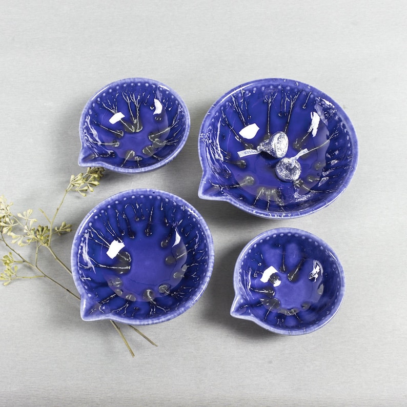 May include: Four blue ceramic bowls with a white glaze and a crackled finish. The bowls are in different sizes and have a unique design.