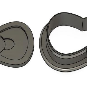 May include: A metal cookie cutter shaped like a bow. The cutter has a detailed design with a center circle and two loops.