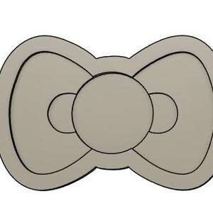 May include: A gray bow-shaped cookie cutter with a circle in the center and two smaller circles on each side.