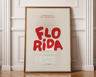 Könnte beinhalten: Ein gerahmtes Poster mit einem roten und weißen grafischen Design, auf dem "Sunshine State of Mind / Paradise Found" und "Florida" in einer fetten, verspielten Schrift stehen. Das Poster enthält auch den Text "Est. 1845".