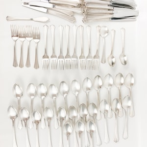 May include: A set of silver flatware, including knives, forks, and spoons. The flatware is arranged in rows on a white background.