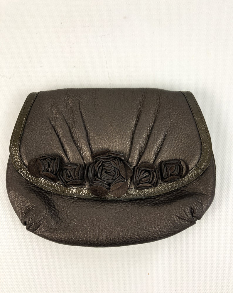 May include: A brown leather clutch purse with a decorative row of fabric roses across the front.