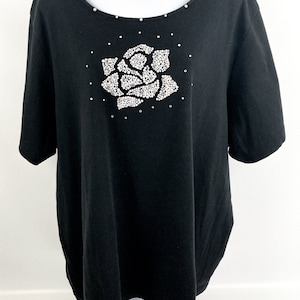 May include: Black short-sleeved t-shirt with a large rhinestone rose design on the front.