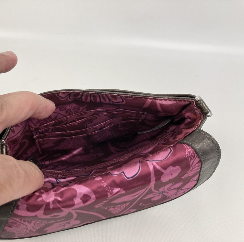 May include: The inside of a small, gray, fabric purse with a pink floral lining. The purse has multiple card slots and a zippered pocket.