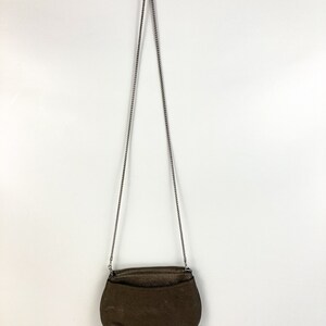 May include: A brown leather crossbody bag with a silver chain strap.