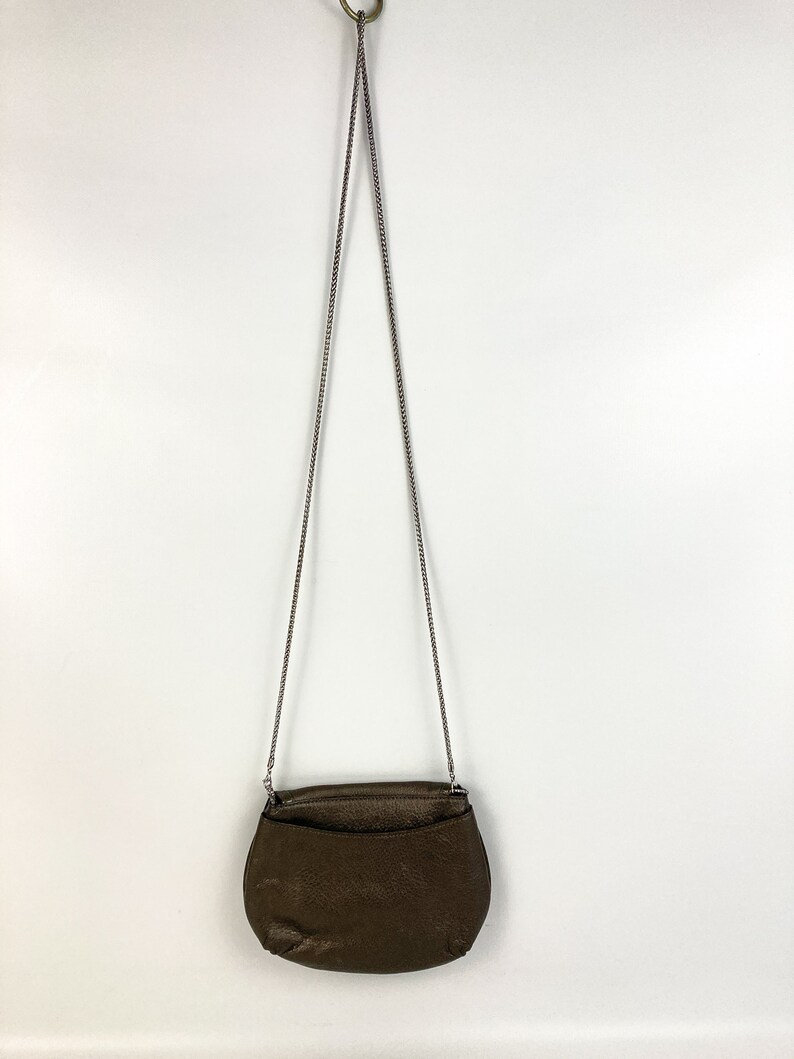 May include: A brown leather crossbody bag with a silver chain strap.