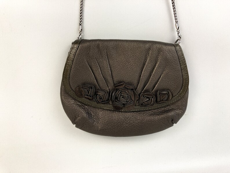 May include: A brown leather crossbody bag with a silver chain strap and a floral design on the front flap.