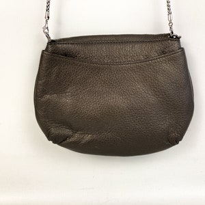 May include: A brown leather crossbody bag with a silver chain strap.