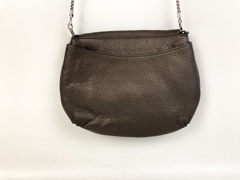 May include: A brown leather crossbody bag with a silver chain strap.