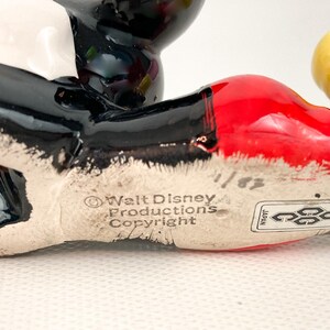 May include: A ceramic Mickey Mouse figurine, featuring black, red, white, and yellow colors. The base of the figurine has the text "Walt Disney Productions Copyright" and a "Japan" sticker.